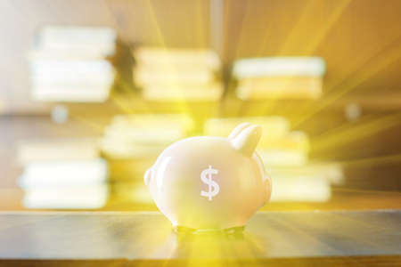 Pig money box on table. Blurred background, Blur bookshelves at book store backgroundの写真素材