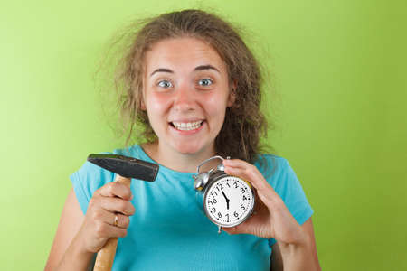 Portrait of shocked girl holding round clock isolated and hummer on yellow wall background in studio. People sincere emotions, lifestyle concept. Mock up copy spaceの写真素材