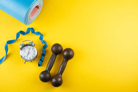 Alarm clock and fitness equipment with bottle on color backgroundの写真素材
