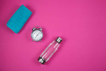 Alarm clock and fitness equipment with bottle on color backgroundの写真素材