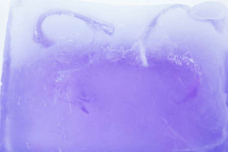 Close-up, shallow focus of a bar of natural soap with engraved letters on its side. Translucent in colour, the soap is seen laying on a natural wooden surface in a bathroom.の写真素材