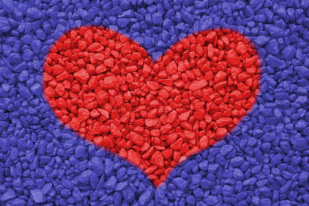 Texture of small decorative stones. Red heart on blue background. Concept of love, romance and valentine's day.の写真素材
