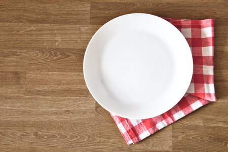 Empty white plate and towel over wooden table background. Copy space and place for meal. Top view.の写真素材