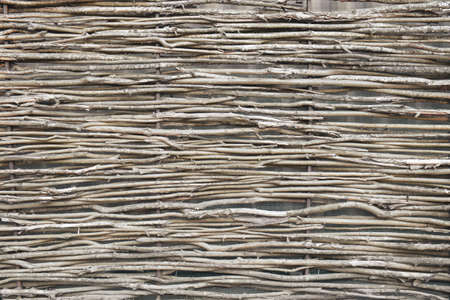 Wattle fence of dry horizontal twigs as the background. Traditional rustic fence. Abstract wooden backdrop.の写真素材