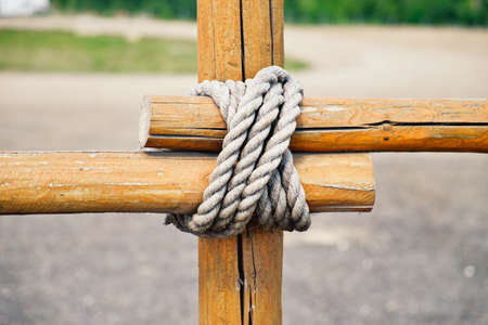 Close-up fragment of wooden fence. Wooden logs tied with strong rope. Decorative knot element.の写真素材