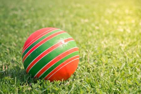 Close-up of single children's rubber ball multicolor ball on bright green grass. Summer playing games. Childhood concept.の写真素材