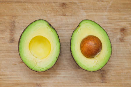 Two pieces of sliced avocado on wooden background. Top view on ripe avocado.の写真素材