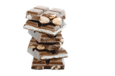 The chocolate pieces of different types stacked on white background.の写真素材