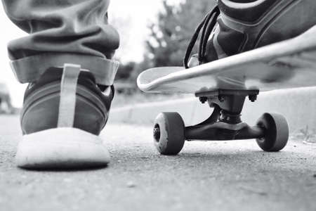 Close-up fragment of skateboard and feet, monochrome retro stylized photo. Young skateboarder...