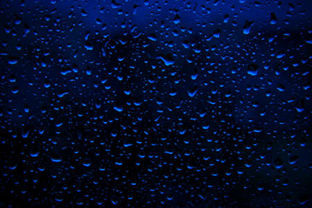Water rain drops on deep blue surface as background. Abstract backdrop.の写真素材