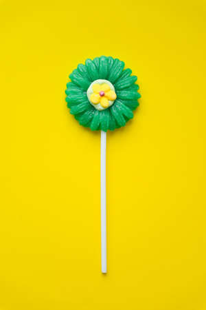 Lollipop in shape of flower on yellow background. Lollipop candy top view.の写真素材