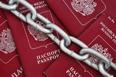 Large and strong metal chain closes the passports with red covers. Sanctions and iron curtain concept.の写真素材