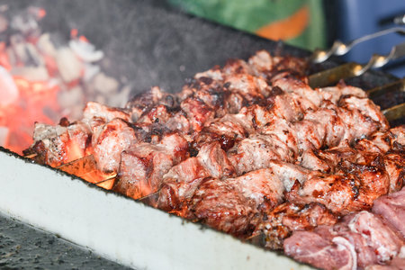 Shish kebab on the skewers in brazier. Fresh ruddy meat for barbecue grill on fire outdoor.の写真素材