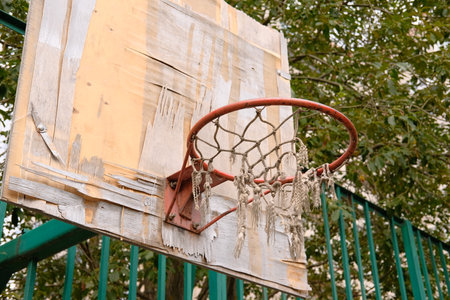 Abandoned, damaged and unused basketball backboard. Basket with torn net.