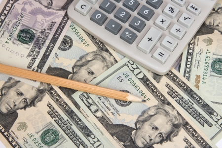 Calculator and pencil on twenty dollar bills isolated on white backgroundの写真素材