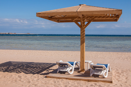 Sandy tropical beach with two chaise loungesの写真素材