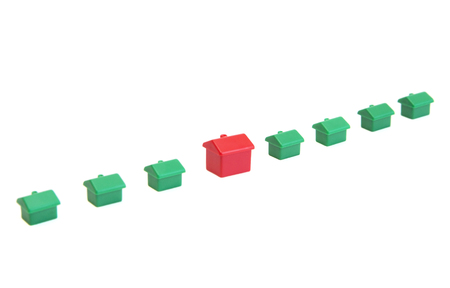 One red and seven green toy house on a white backgroundの写真素材