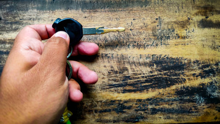 hand holding a key on a wooden tableの写真素材