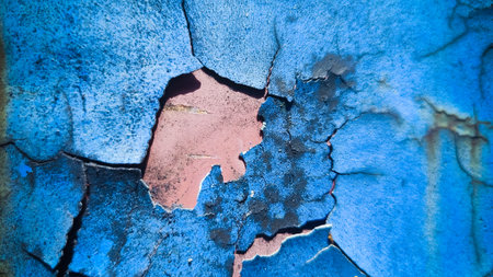 Intricate cracked patterns of blue paint expose dark textured layers and reddish-brown hints underneathの写真素材