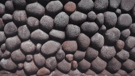 Background of black pebble stone wall texture. Close up.