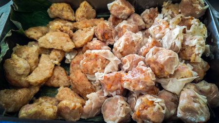 A mix of dim sum and crispy dumplings served in a tray lined with banana leavesの写真素材