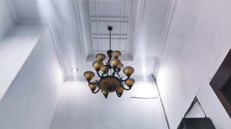 A low angle shot of a luxury vintage chandelier hanging from a white decorative coffered ceiling in a grand room.の写真素材