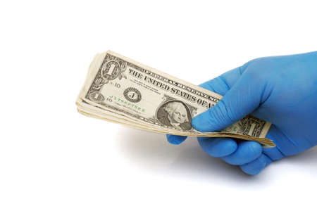 hand in blue medical glove holding dollar banknotes isolated on white backgroundの写真素材