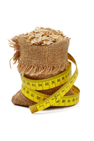 oat rolled cereals in full burlap sack with measure tape isolated on white backgroundの写真素材
