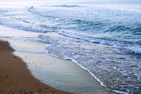calm waves washing ashore in the morningの写真素材