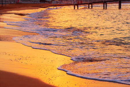 calm waves washing beach in sunrise in early morningの写真素材