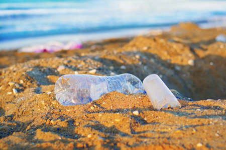 plastic bottle and cups on a beachの写真素材