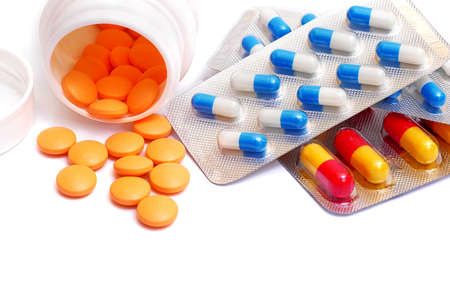 pills spilled from bottle and capsules in blister packs isolated on white background