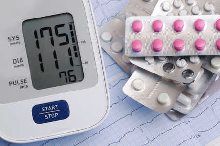 automatic blood pressure meter and pills on cardiogram graph backgroundの写真素材