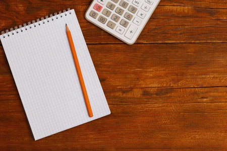 top view of calculator, notepad and pencil on wooden background with copy spaceの写真素材
