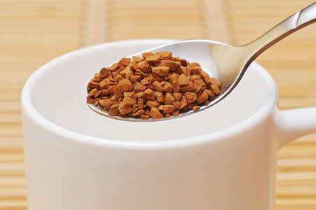 closeup of spoon of instant coffee and white cupの写真素材