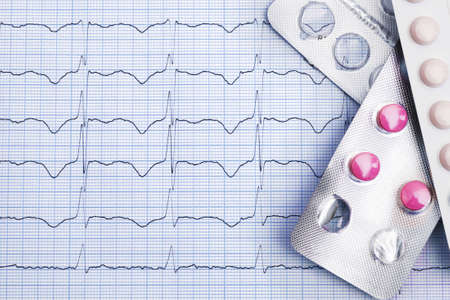 pills in blister packs on cardiogram graph papepr background with copy spaceの写真素材
