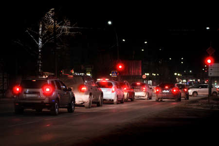 cars in a row before stop signal of traffic light in the darkness