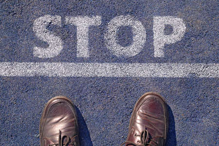 man in shoes standing before stop sign painted on asphalt, top viewの写真素材