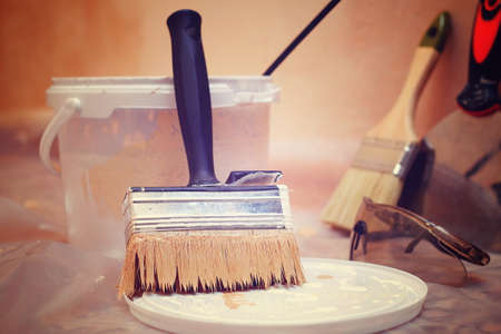 close-up on paintbrush in front of tin of paint with other tools in background, tonedの写真素材