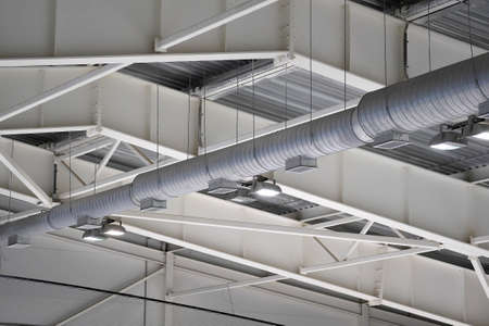 steel girders of building roof with ventilation duct and spotlights