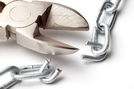 macro of broken chain and cutter on white backgroundの写真素材