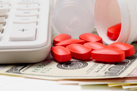 maro view of calculator, spilled red pills and dollar banknotes, concept for medical expensesの写真素材