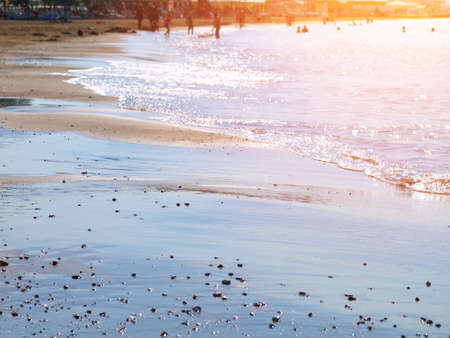 sea waves on sand beach with swimming peoples in background, toned, sunlight effectの写真素材