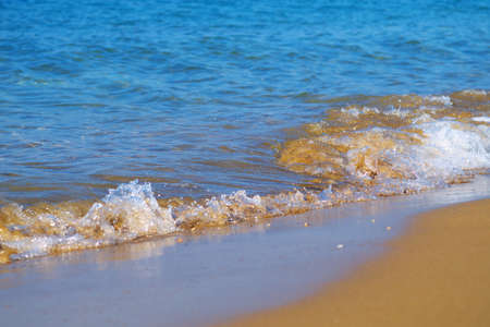 closeup of sea waves washing over sand on beachの写真素材