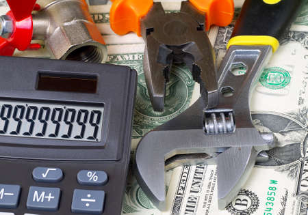 calculator with big sum on display and plumber tools on banknotes background, expensive plumbing conceptの写真素材