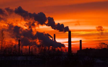 Smoking factory chimneys in morning back lighted by rising sunの写真素材