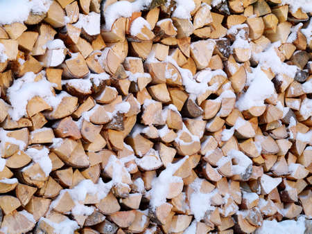 woodpile of chopped firewoods outdoor under snow in winter