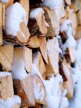 woodpile of chopped firewoods outdoor under snow in winter, closeup, shallow depth of field