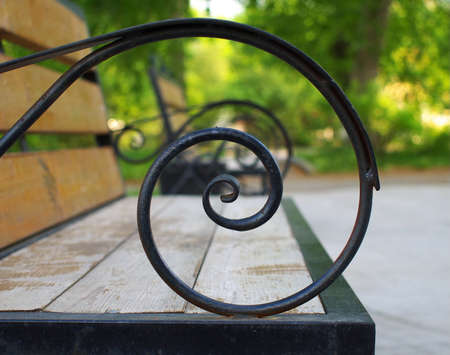Wooden bench armrest made from hand forged spiral rod, shallow depth of fieldの写真素材