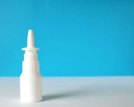 white nasal spray bottle closeup in front of blue background with a copy spaceの写真素材